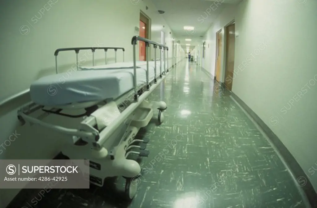 A wheeled stretcher sits against the wall of a hospital corridor.