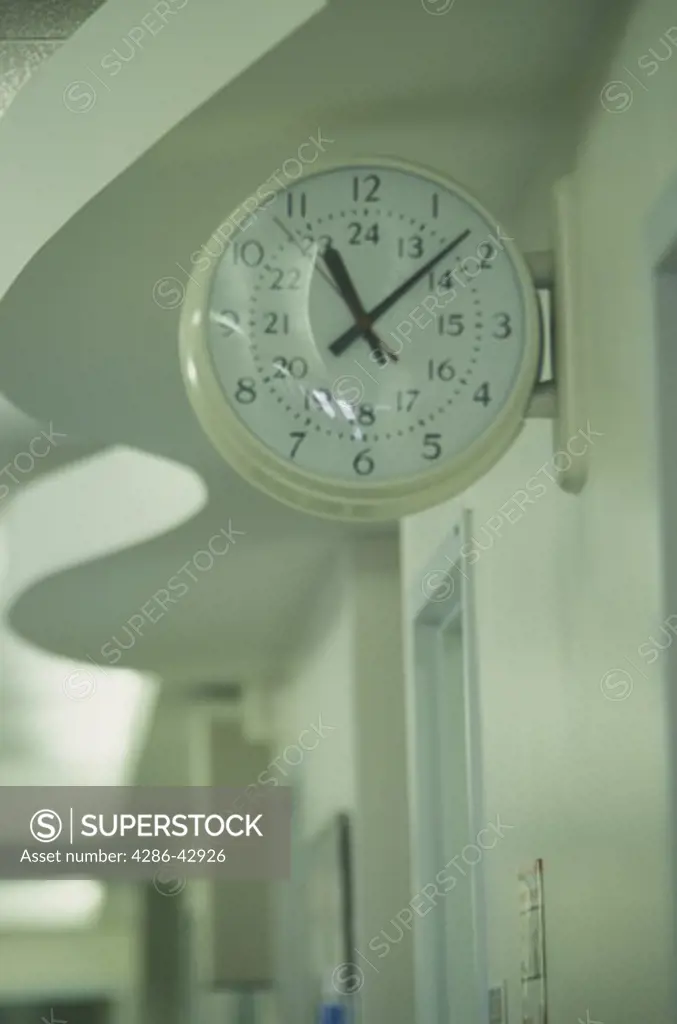 A clock is set high up on the wall of a hospital corridor.