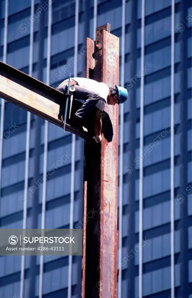 Construction worker on a steel beam connecting girders together. 