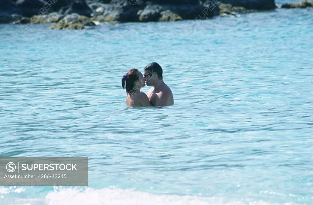 Romantic couple kiss in the blue waters of the Caribbean Sea at Coki Beach, St. Thomas, U.S. Virgin Islands. 
