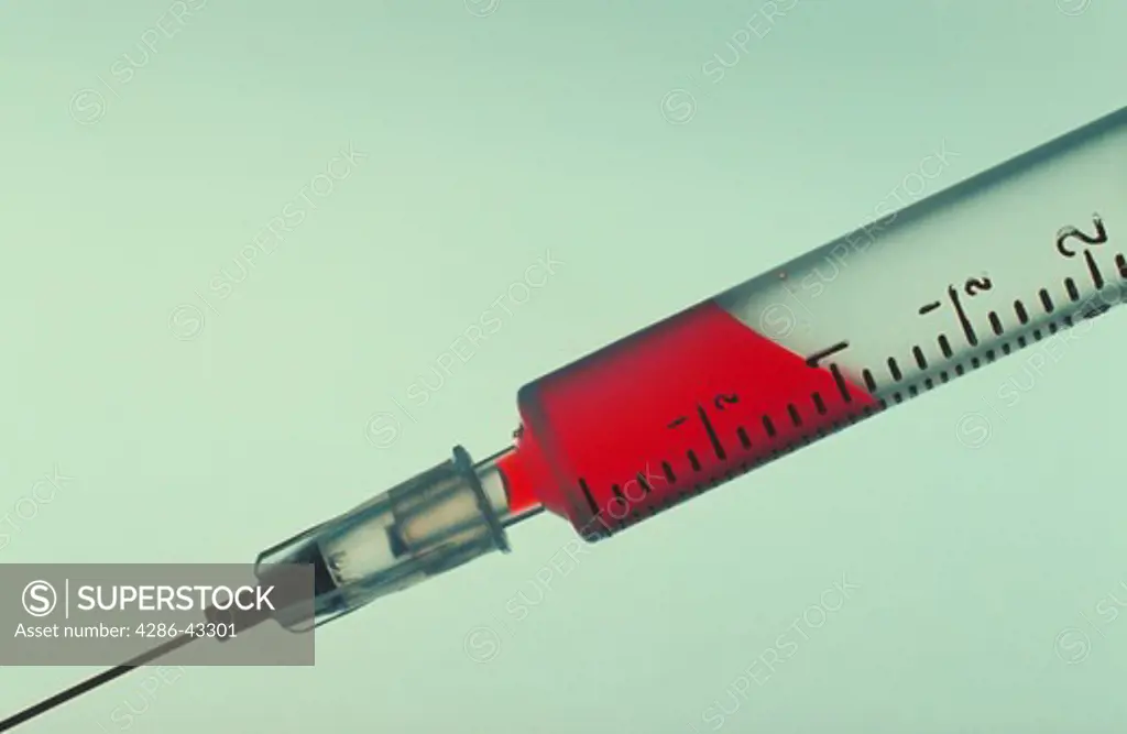 Still life of a Hypodermic syringe and needle partially filled with a red fluid.