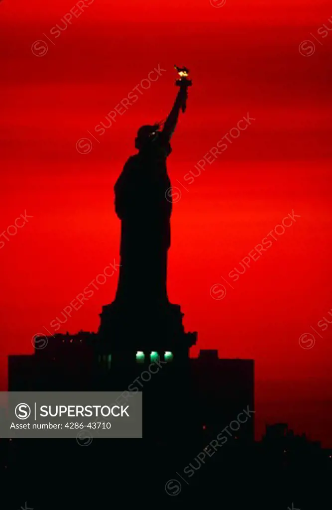 Silhouette of Statue of Liberty at sunrise.