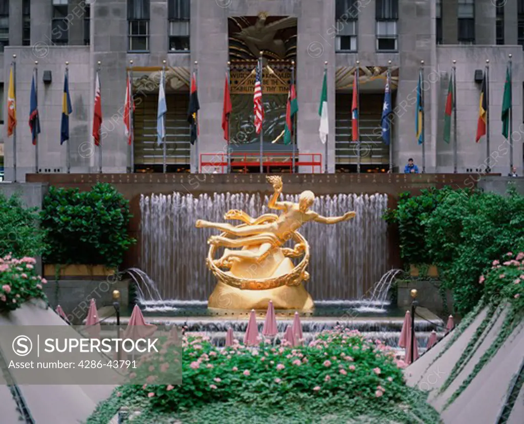 International flags standing above the golden statue and waterfalls on the plaza at Rockefeller Center in New York, New York.