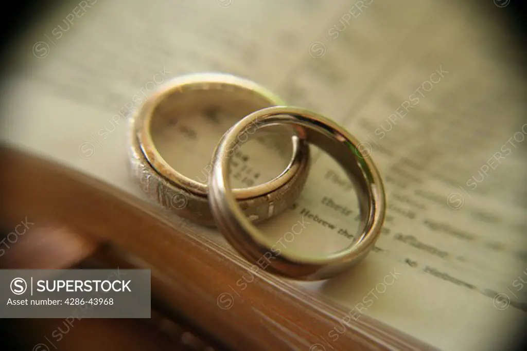 Two white gold wedding rings on an open Bible