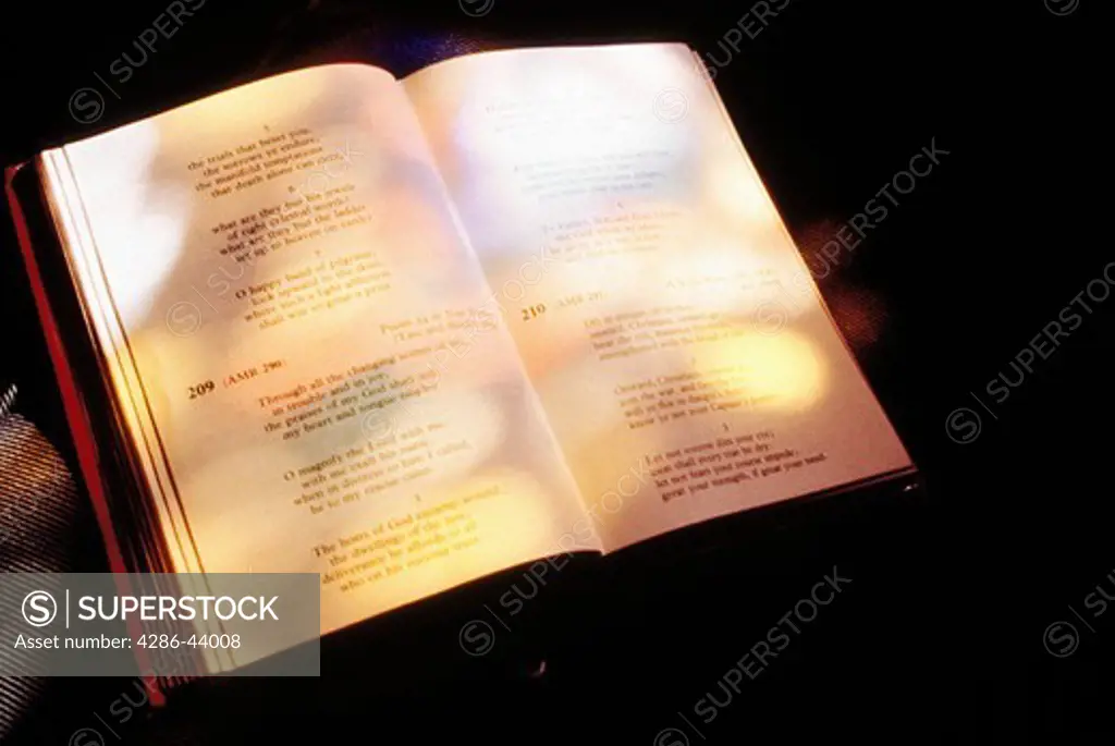 Stained glass lights filter onto an open Bible