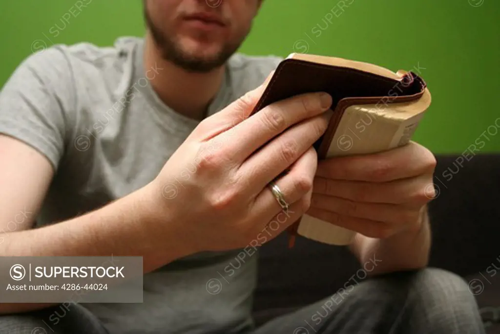 Young blond man reading the Bible with bright green background