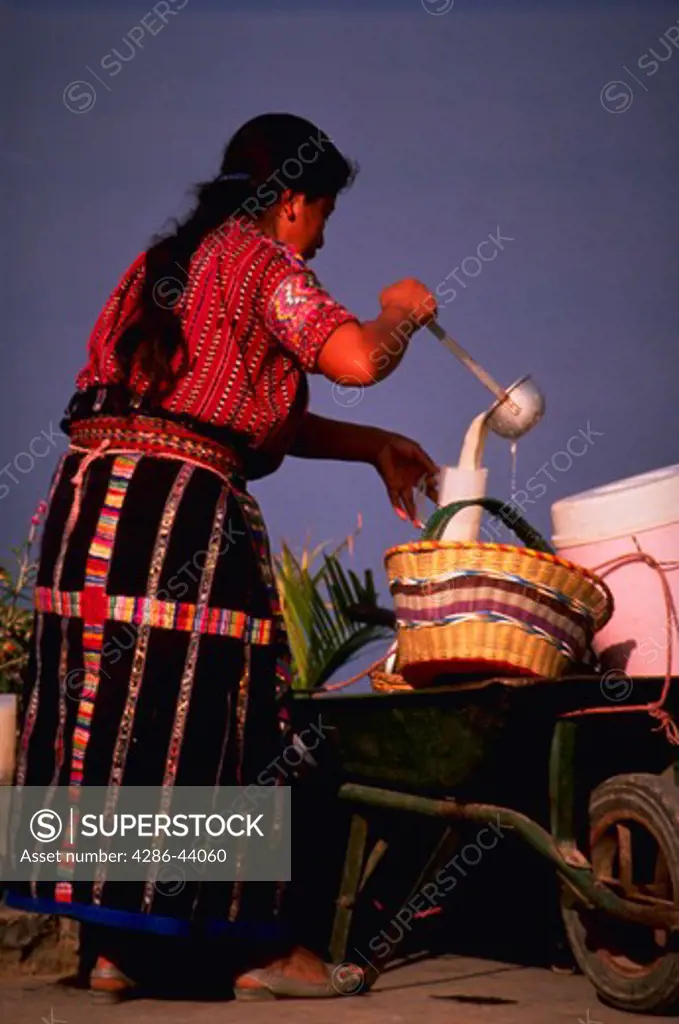 GUATEMALA WOMAN VENDOR SELLING MILK FROM A WHEELBARROW