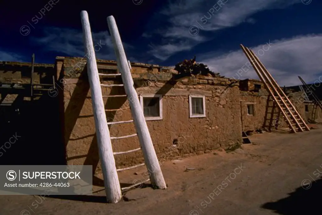INDIAN ADOBE HOUSE WITH LADDERS TO HEAVEN IN ACOMA NEW MEXICO