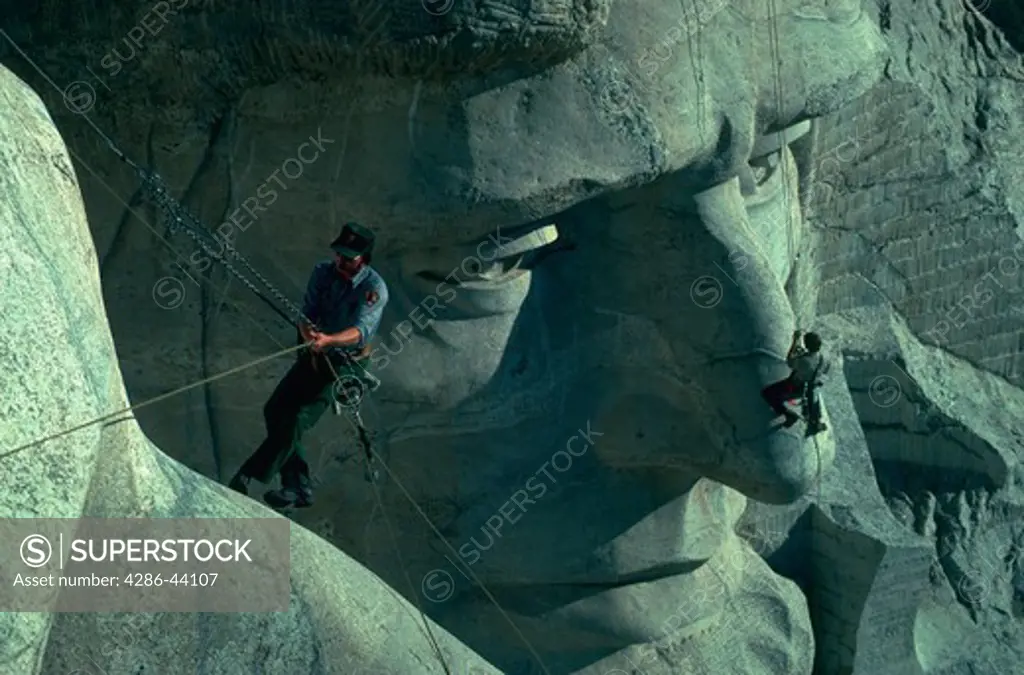 Two workers examine cracks in the faces at Mt. Rushmore.