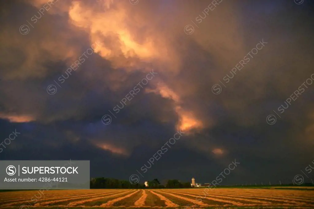 Sunset illuminates a passing thunderstorm over a farm in eastern South Dakota.