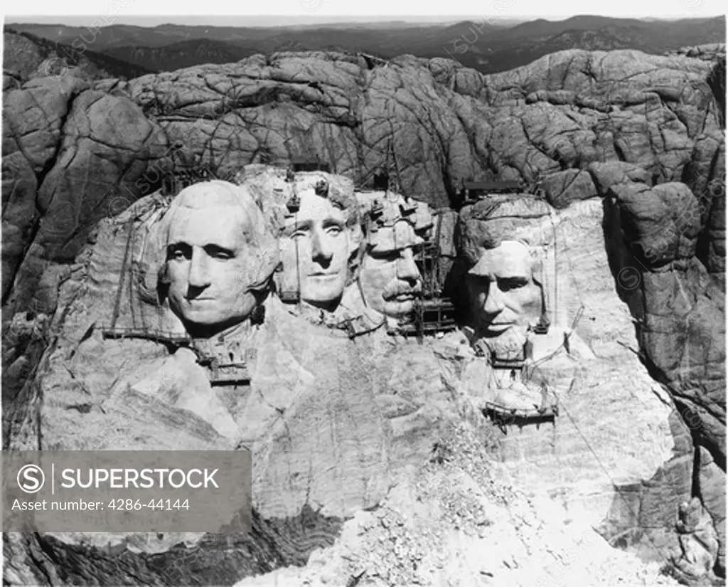 A rare view of Mt. Rushmore National Memorial during the final months of its construction, 1941. Scaffolding below, and worker's buildings visible on top. All four figures were to be carved to waist level but the death of the sculptor Gutzon Borglum led is his son to declare the work finished that year.