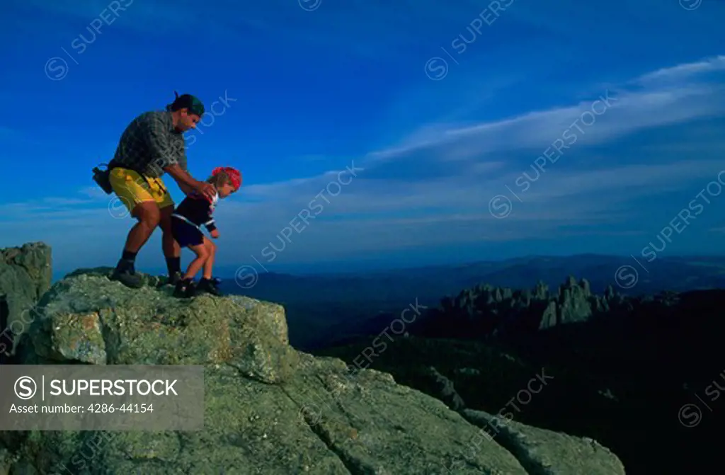 A father and son carefully begin a descent of Harney Peak high in the Black Hills of South Dakota.