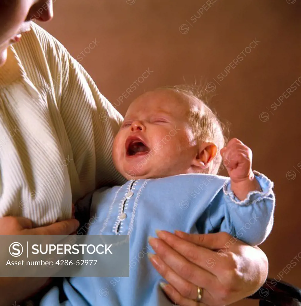 Mother holding her crying infant close to her bosom. 