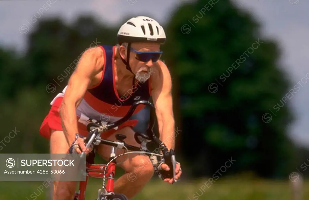 Senior man wearing a helmet and riding in a bicycle race.