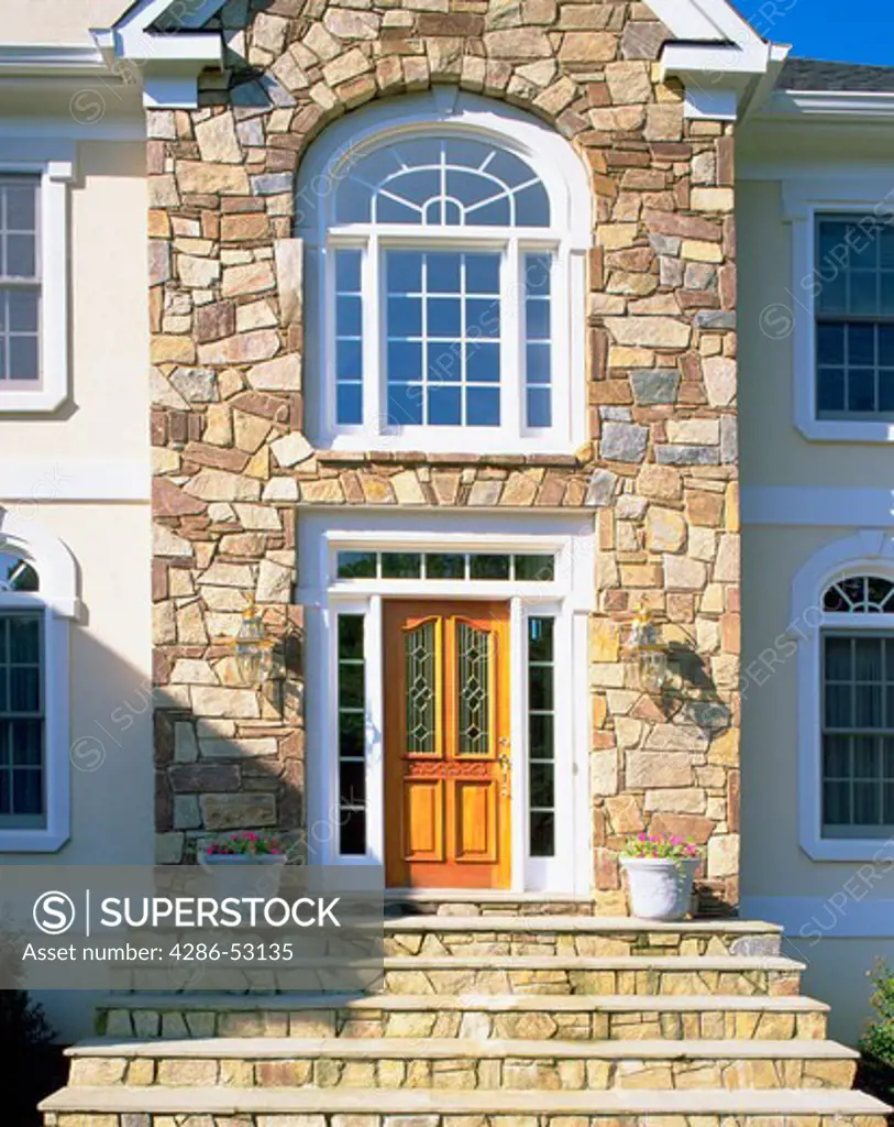 Front entrance of elegant house with stone facade and steps. Property released.