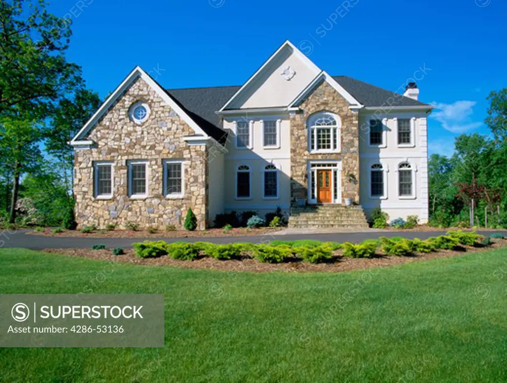 Exterior front view of elegant two story home with stone facade and steps. Property released.