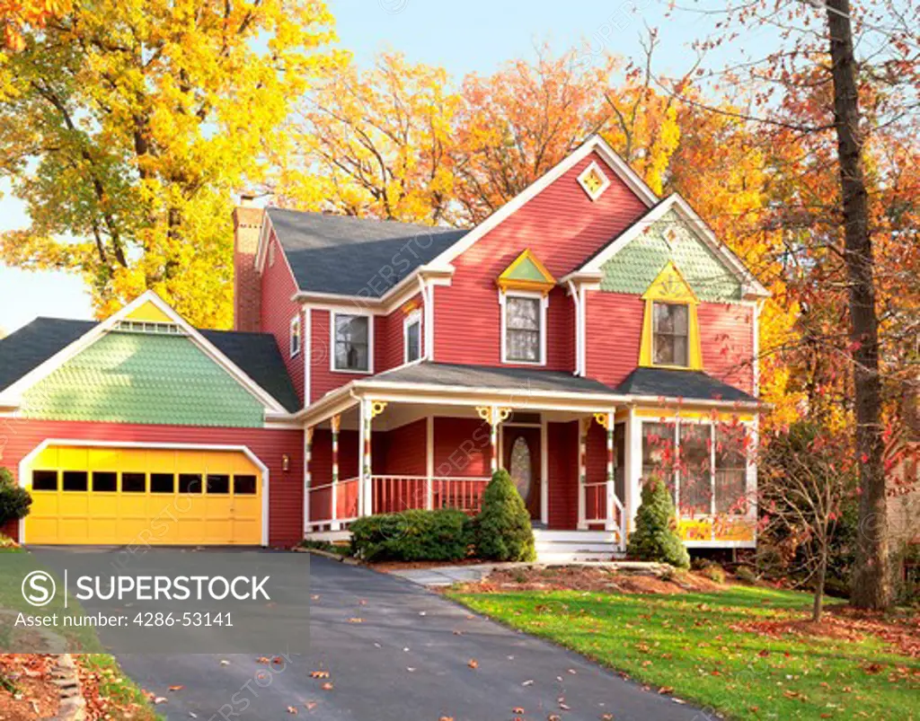 Exterior front view of colorfully painted multi-story clapboard house among golden autumn leaves . Property released.