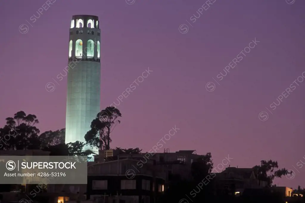 Coit Tower atop Telegraph Hill in San Francisco is illuminated during a purple twilight.