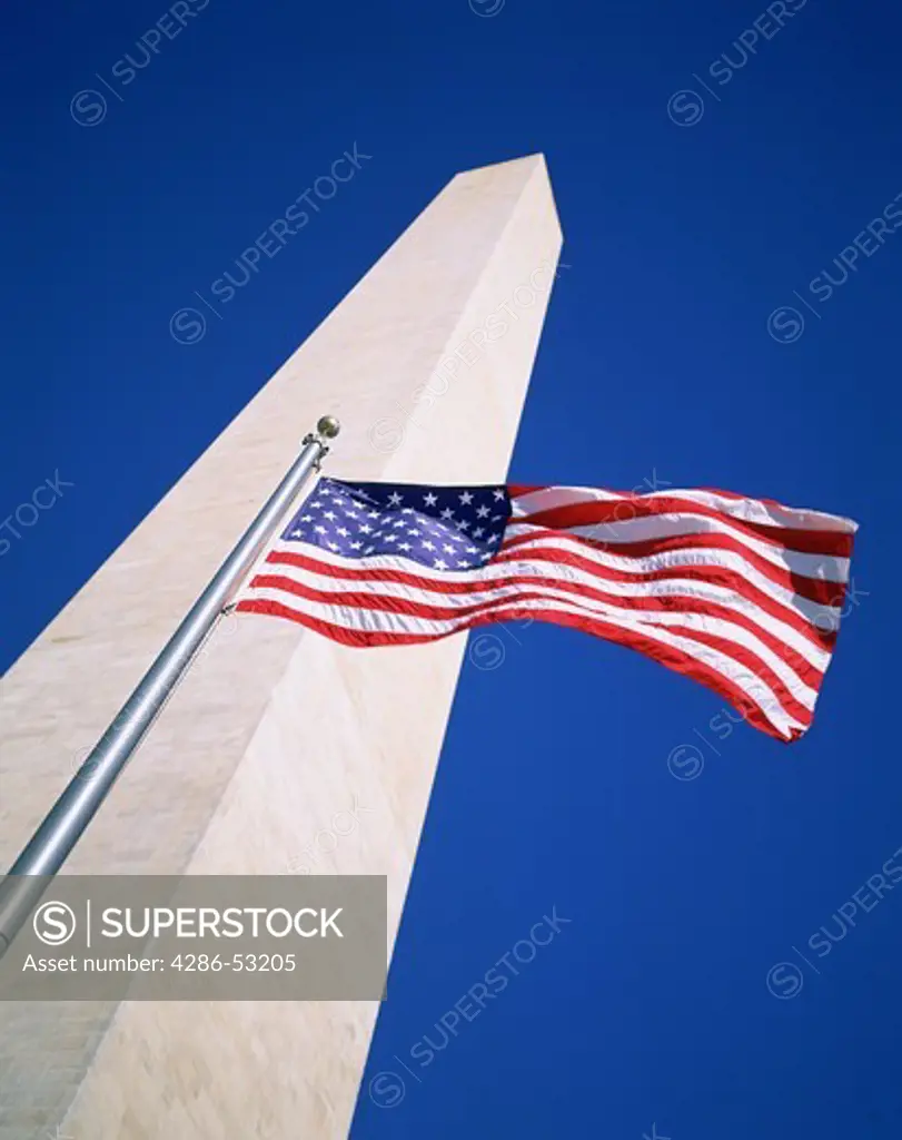 Looking up at the Washington Monument with an American flag flying in the foreground.