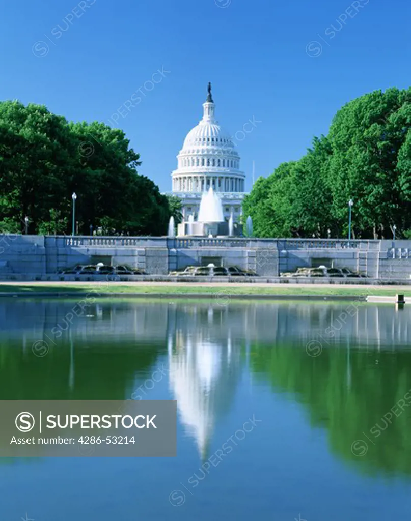 The dome of the U.S. Capitol in Washington D.C. seen from the north. It is reflected in a decorative pool beside a fountain.