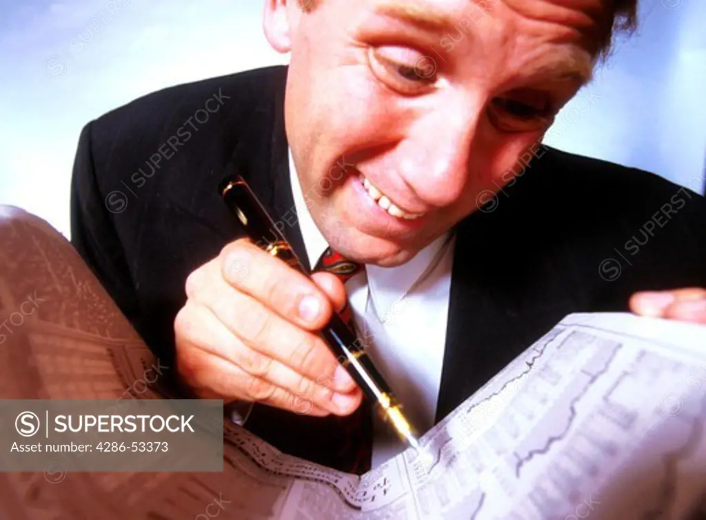 A businessman anxiously looks over the financial pages in the newspaper.