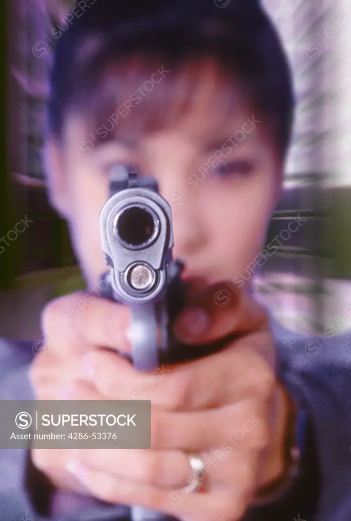 Looking down the barrel of a gun being held by an Asian woman.