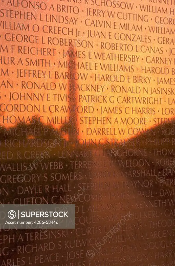 Silhouette of the Washington Monument and the sunrise reflected on names inscribed on the Wall of the Vietnam Memorial, Washington, DC.