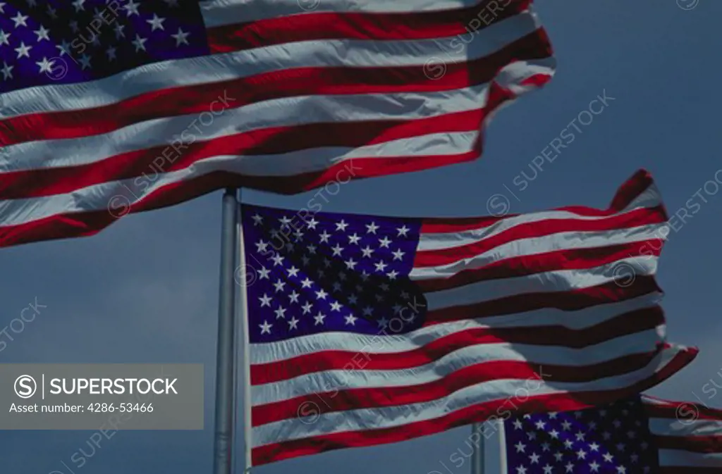 Three American flags waving in the wind.