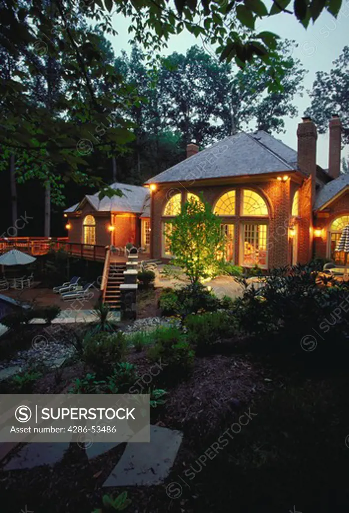 Exterior view of a brick colonial with elaborate pool and patio at dusk.  Property released.