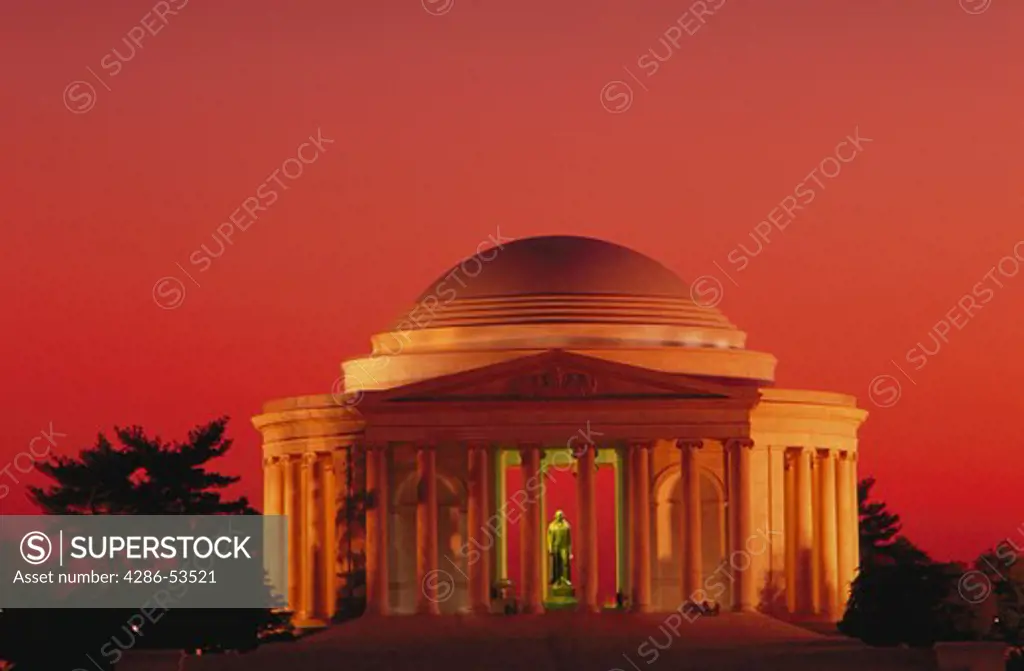 Statue of Thomas Jefferson visible through the columns of the Jefferson Memorial against a sunset sky, Washington, DC.