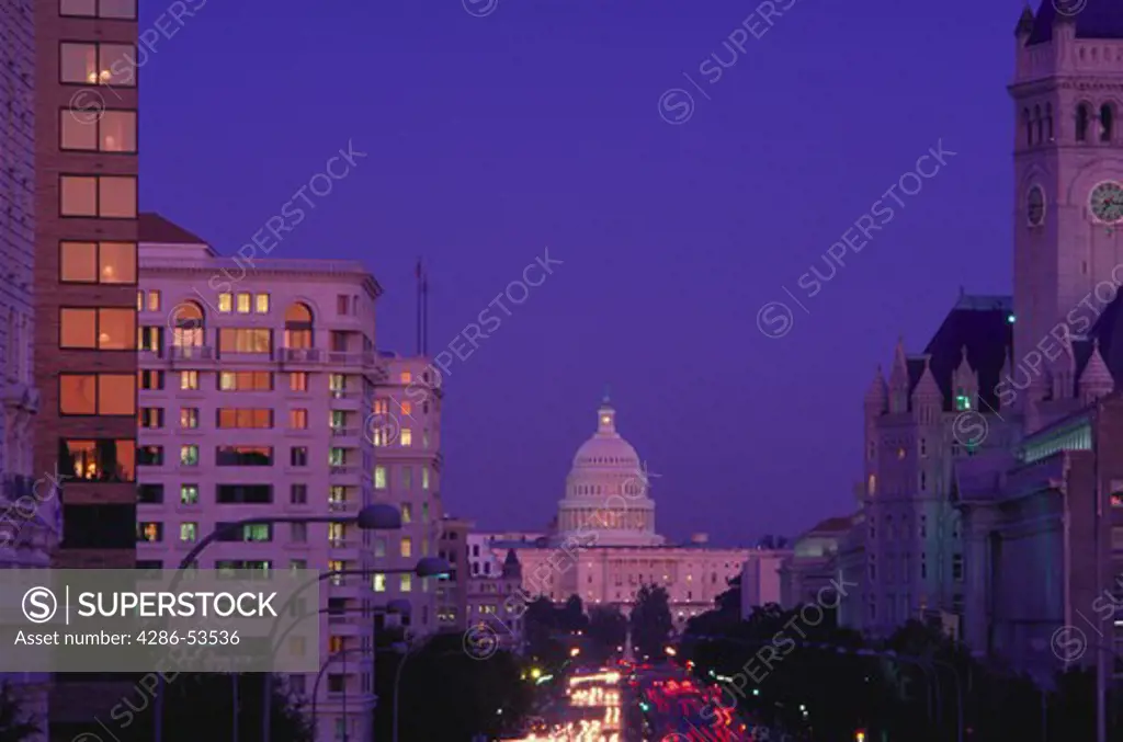 View down Pennsylvania Avenue to the U.S. Capitol with blurred lights of traffic and office buildings at dusk, Washington, DC.