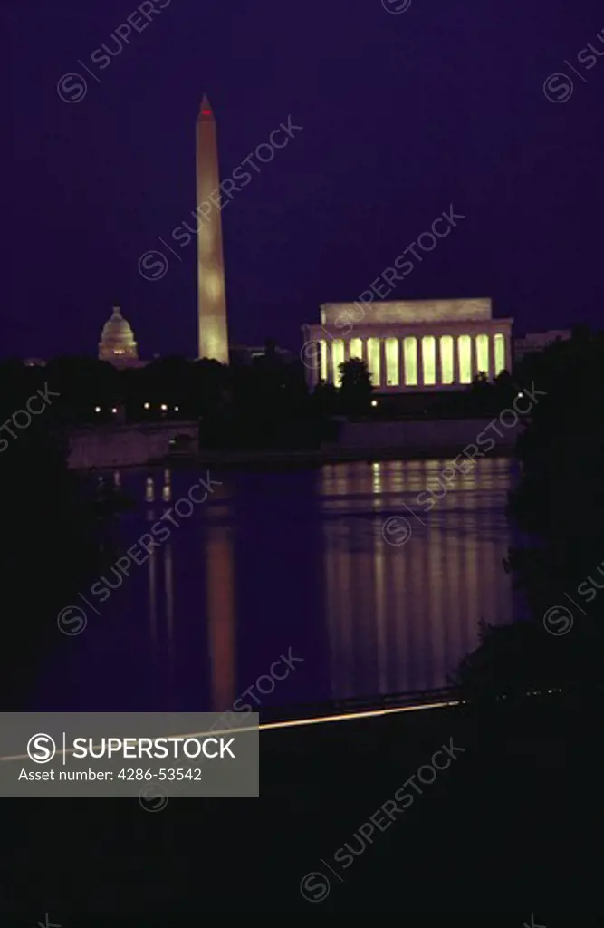 View of the Lincoln Memorial, the Washington Monument and the U.S. Capitol dome at night with lights reflecting on the Potomac River, Washington, DC.