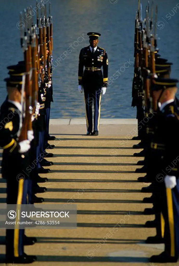 U.S. Army color guard in dress blue uniforms standing at attention under the direction of a sergeant.