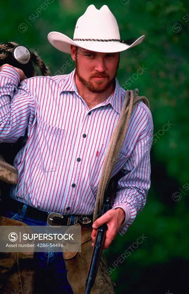 Wrangler carrying a saddle and tack over his shoulder