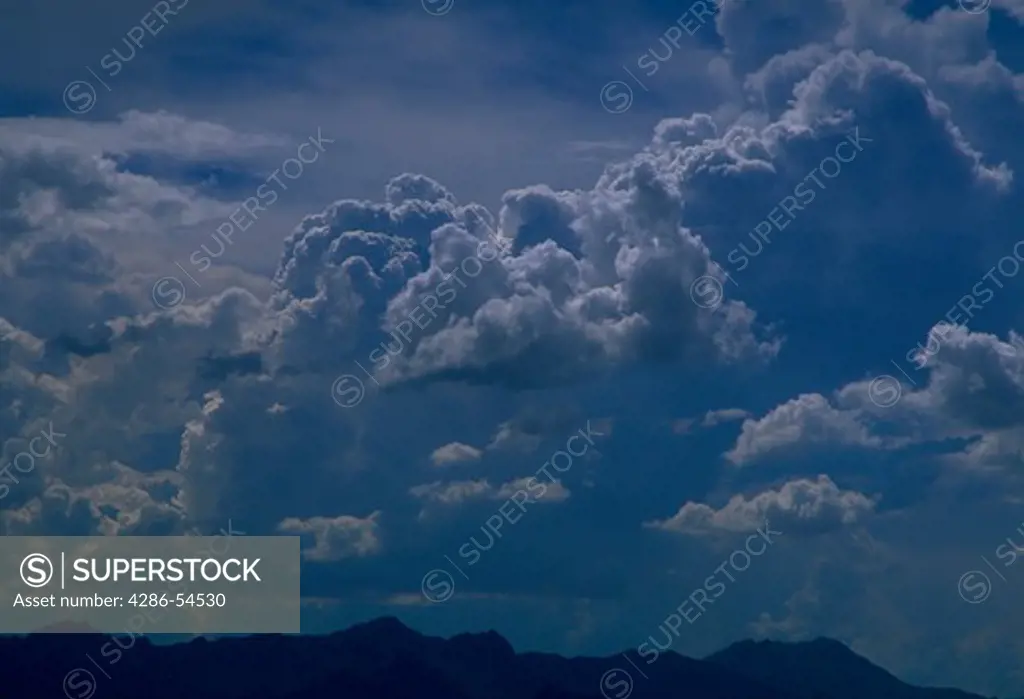 Puffy cumulonimbus clouds forming in blue sky over Tucson, Arizona.