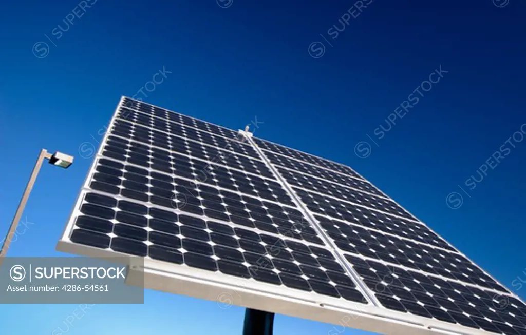 A close-up shot of a solar panel absorbing sunlight with a clear blue sky in the background.