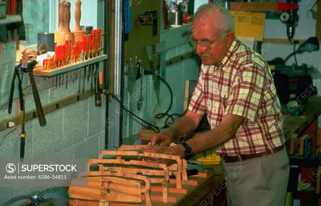 Retiree works on a model boat in woodworking shop at retirement center in Maryland. (model released)