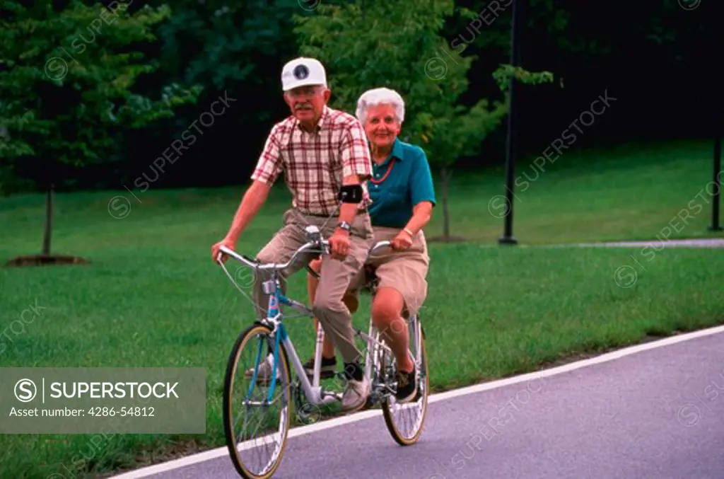 Active senior married couple enjoy a tandem bicycle ride in Maryland. (model released)