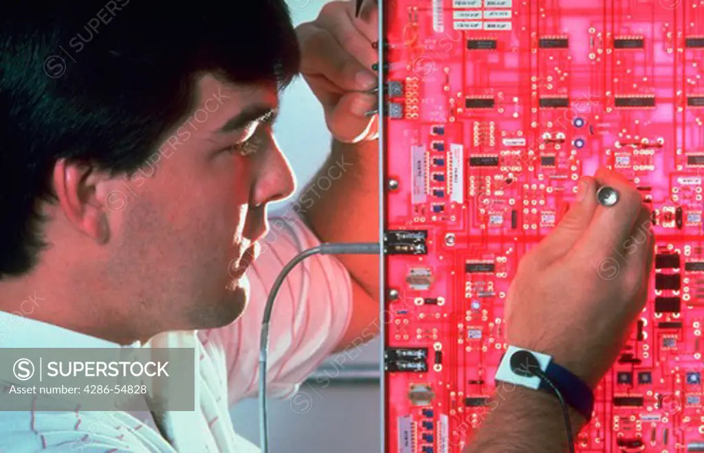 Cellular telephone technician at work on circuit board in Syracuse, New York.