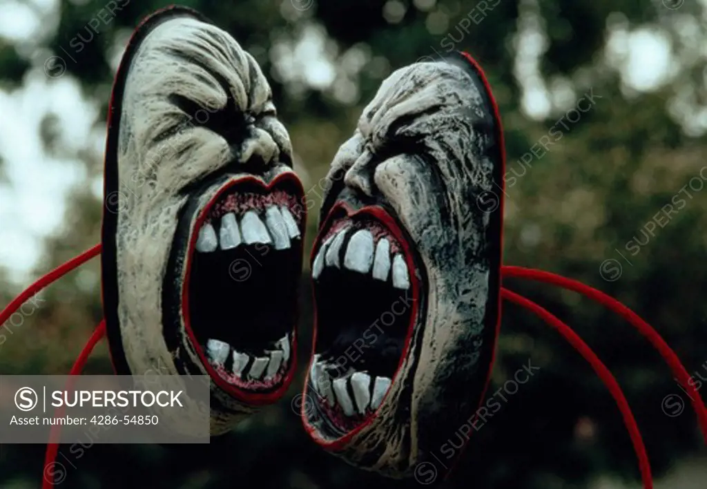 Two screaming masks face off with one another during Trinidad's Mardi Gras carnival. These masks are part of elaborate costumes typical of the annual festival.