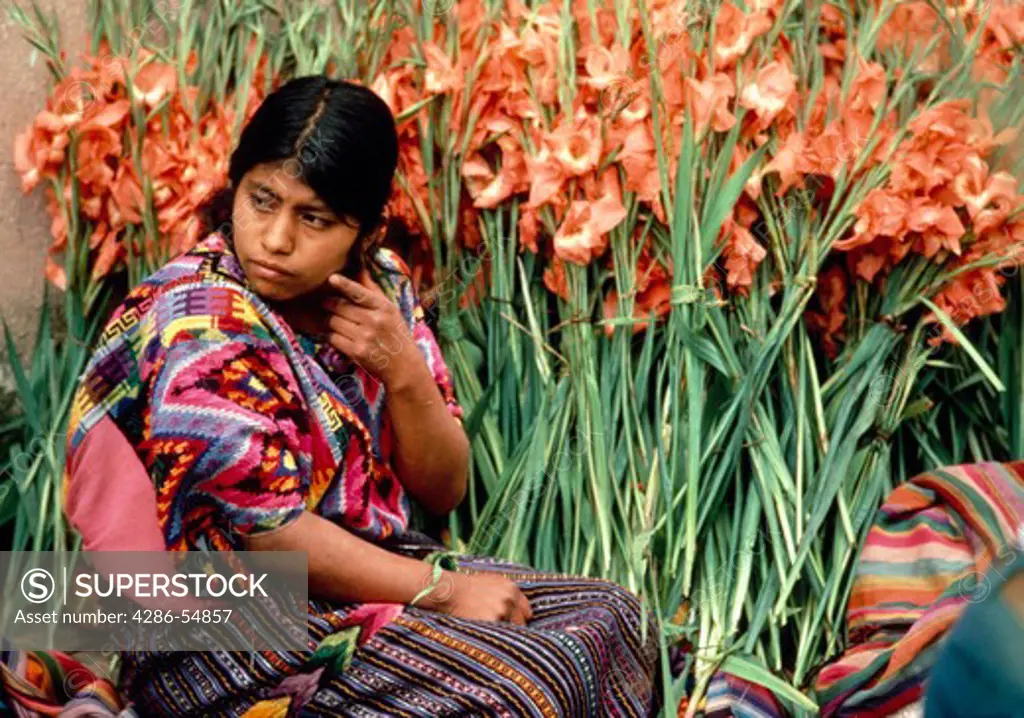 Young Guatemalan Indian woman in traditional dress sells flowers in the market in the village of Chichicastenango, Guatemala.