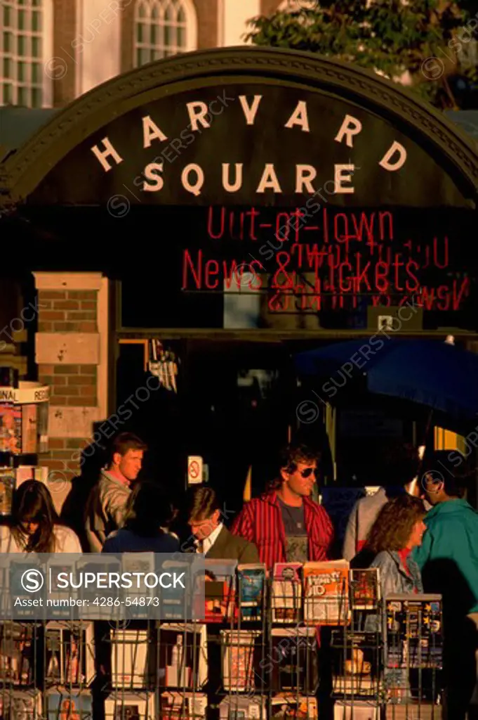 People move past racks of magazines and books at the news stand in the center of Harvard Square, near Harvard University in Cambridge, Massachusetts.