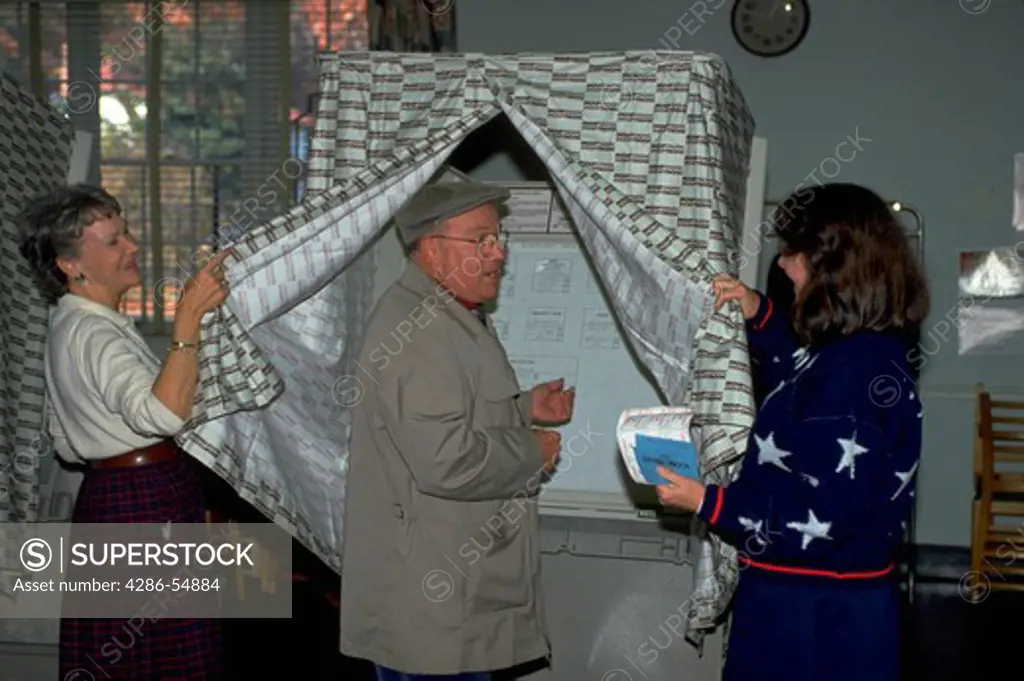 Elderly man prepares to vote as election officials assist him on election day in Arlington, Virginia.