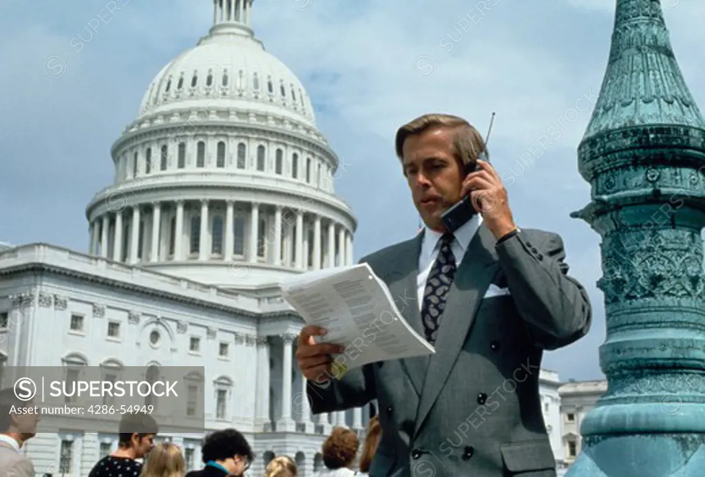 Healthcare industry lobbyist on cellular telephone in front of United States Capitol dome, Washington, DC.