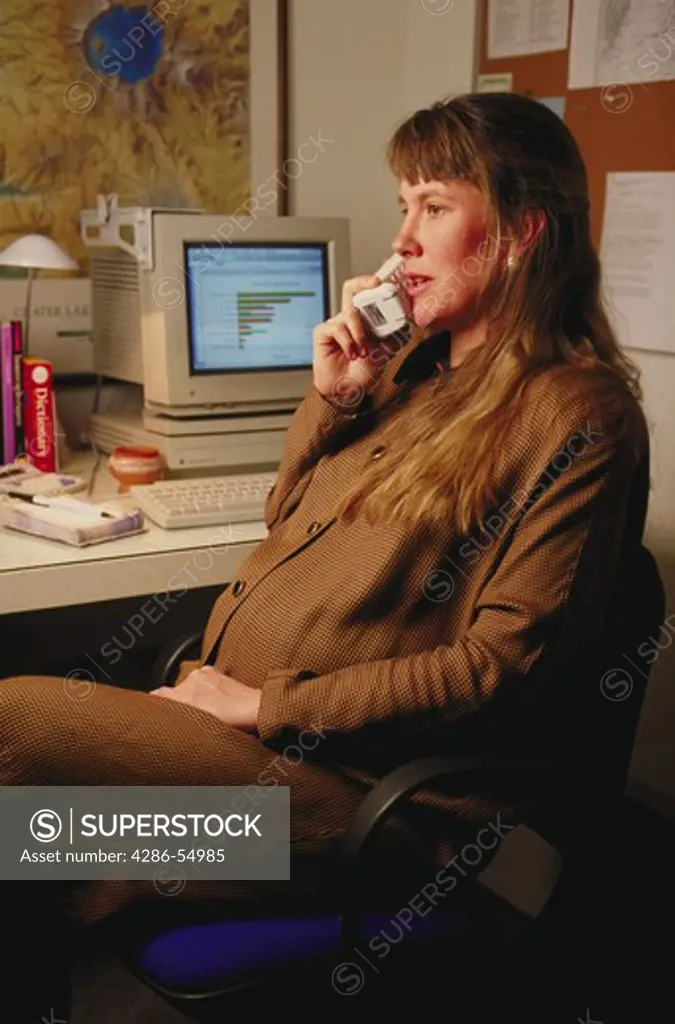 Pregnant woman talking on phone in home office