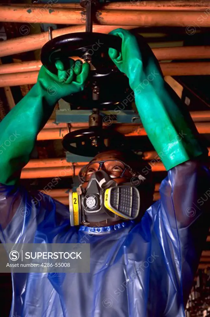 Man wearing protective clothing turning Nomex machine valve at DuPont fivers plant in Richmond, Virginia.