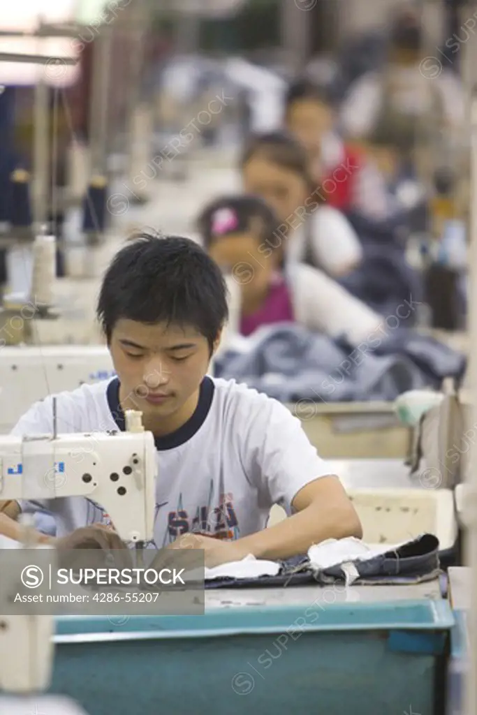 SHENZHEN, GUANGDONG PROVINCE, CHINA - Workers sewing Mango jeans, in garment factory in city of Shenzhen, one of mainland China's first Special Economic Zones, SEZ.