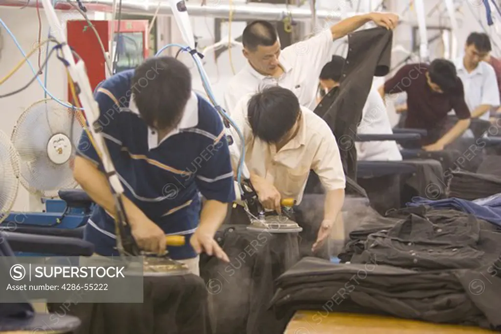 SHENZHEN, GUANGDONG PROVINCE, CHINA - Men ironing finished clothing, in a garment factory in city of Shenzhen, one of mainland China's first Special Economic Zones, SEZ.
