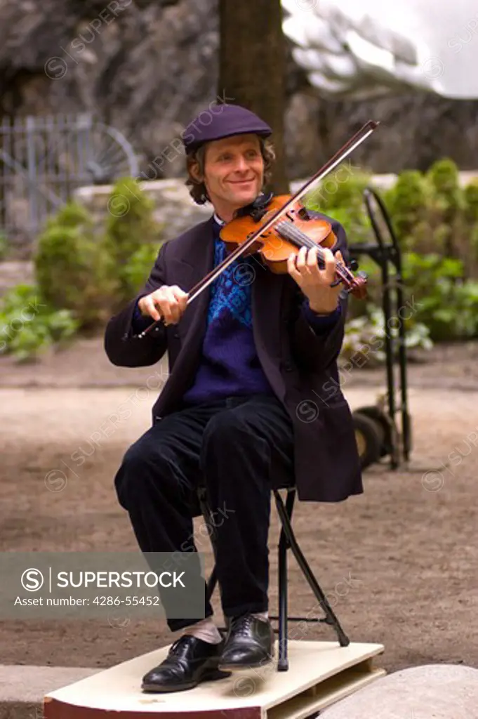 QUEBEC CITY, QUEBEC, CANADA - Jacques Dupuis, traditional Quebec folk music performer, plays violin and taps feet on sound board, on Petit Champlain Street, in Old Quebec City.