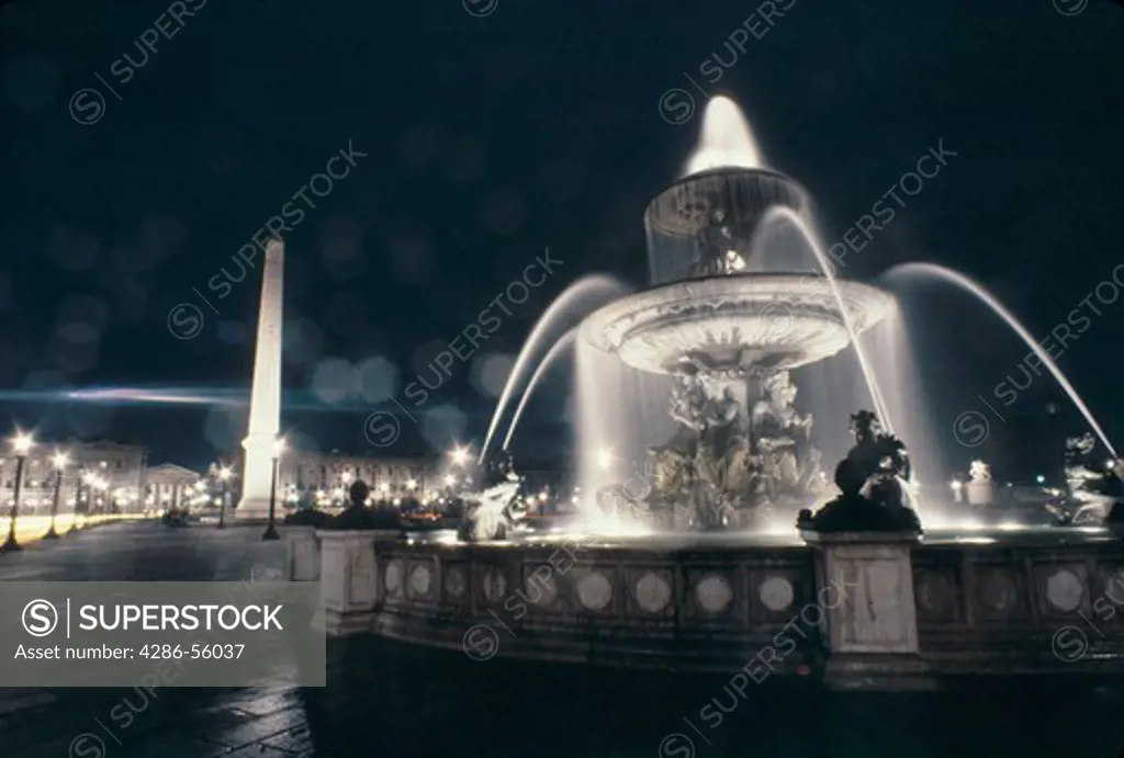 Illuminated fountain at night in the Place de la Concorde, Paris, France. The Obelisk, an Egyptian antiquity, is in the background.